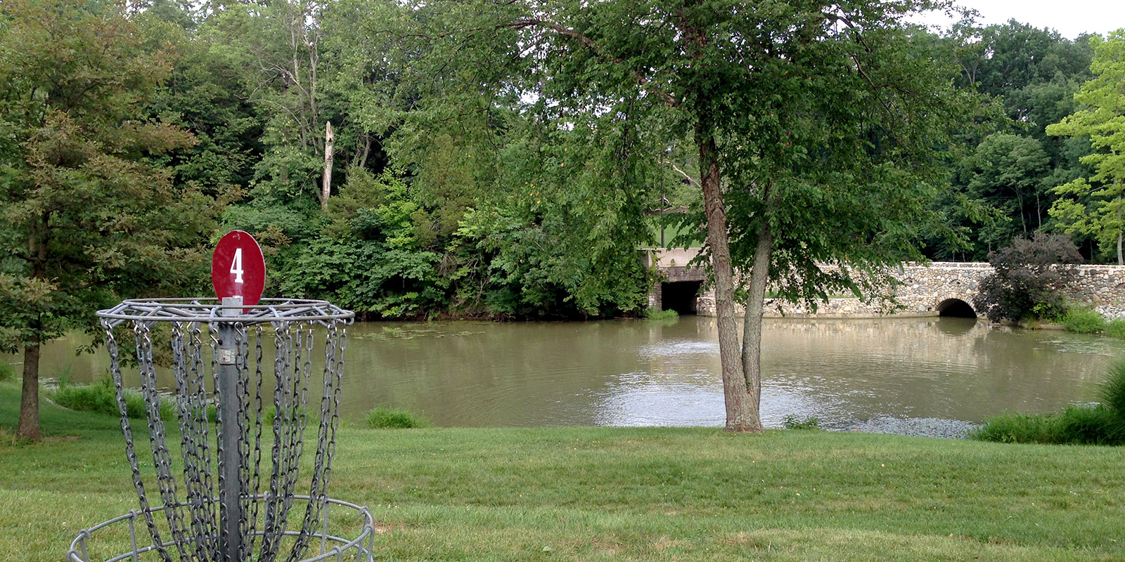 disc golf basket in front of a pond